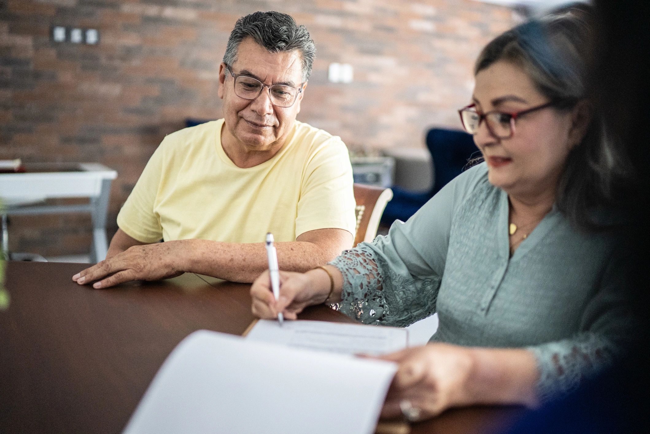 Couple reviewing and signing paperwork at a table